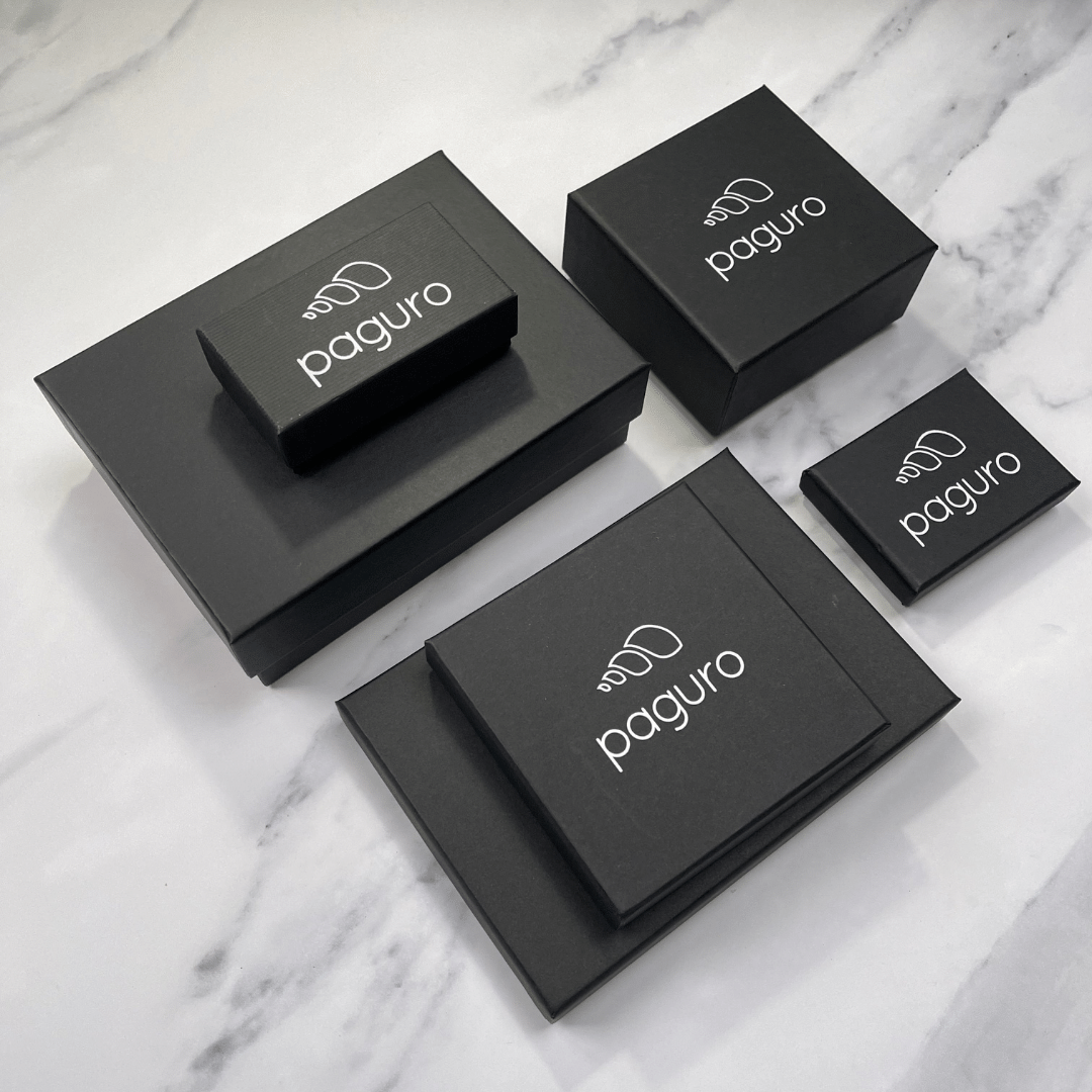 Paguro Upcycle black packaging boxes for recycled rubber bracelet products on marble surface