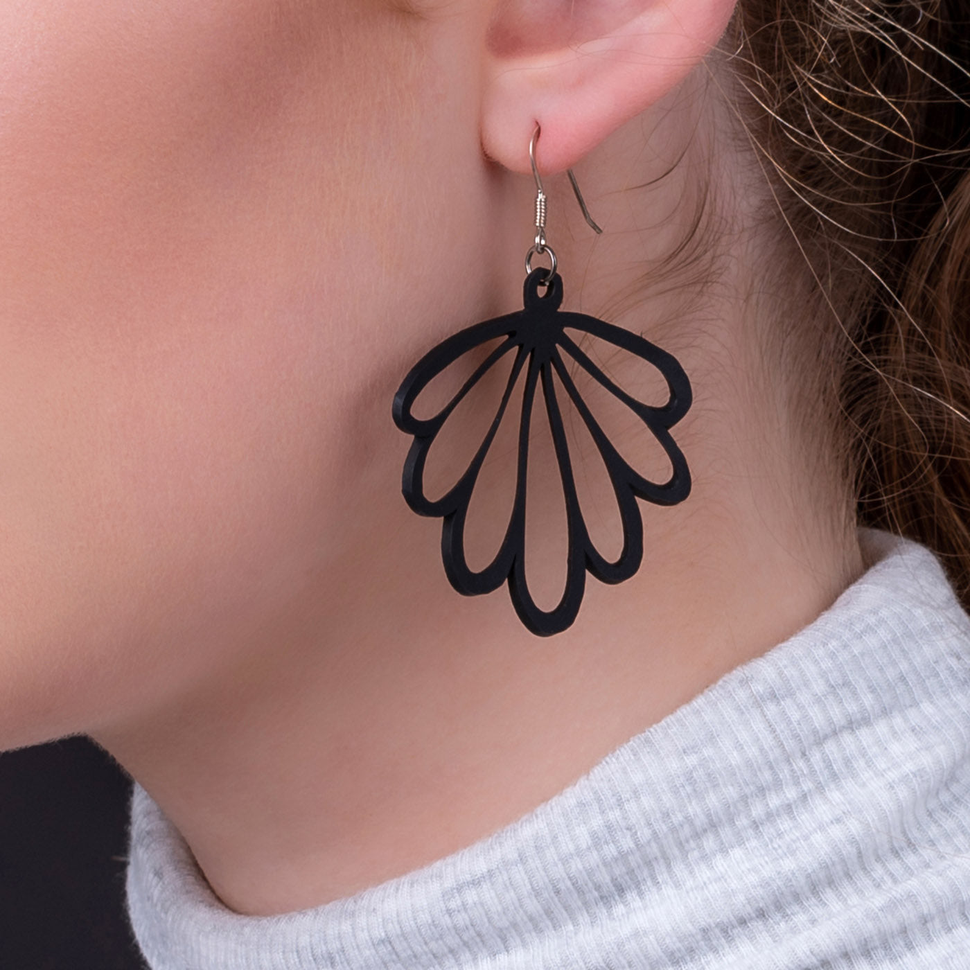 Paguro Upcycle black recycled rubber earrings in a scallop shell design worn on ear