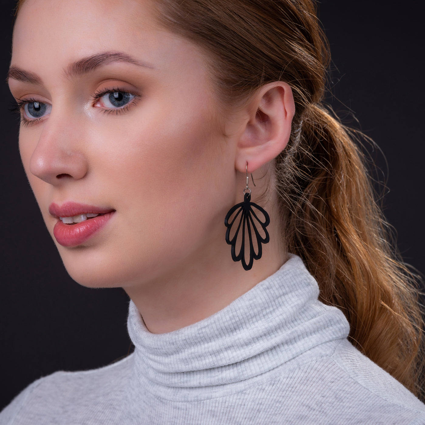 Paguro Upcycle black recycled rubber earrings worn by woman with light gray turtleneck