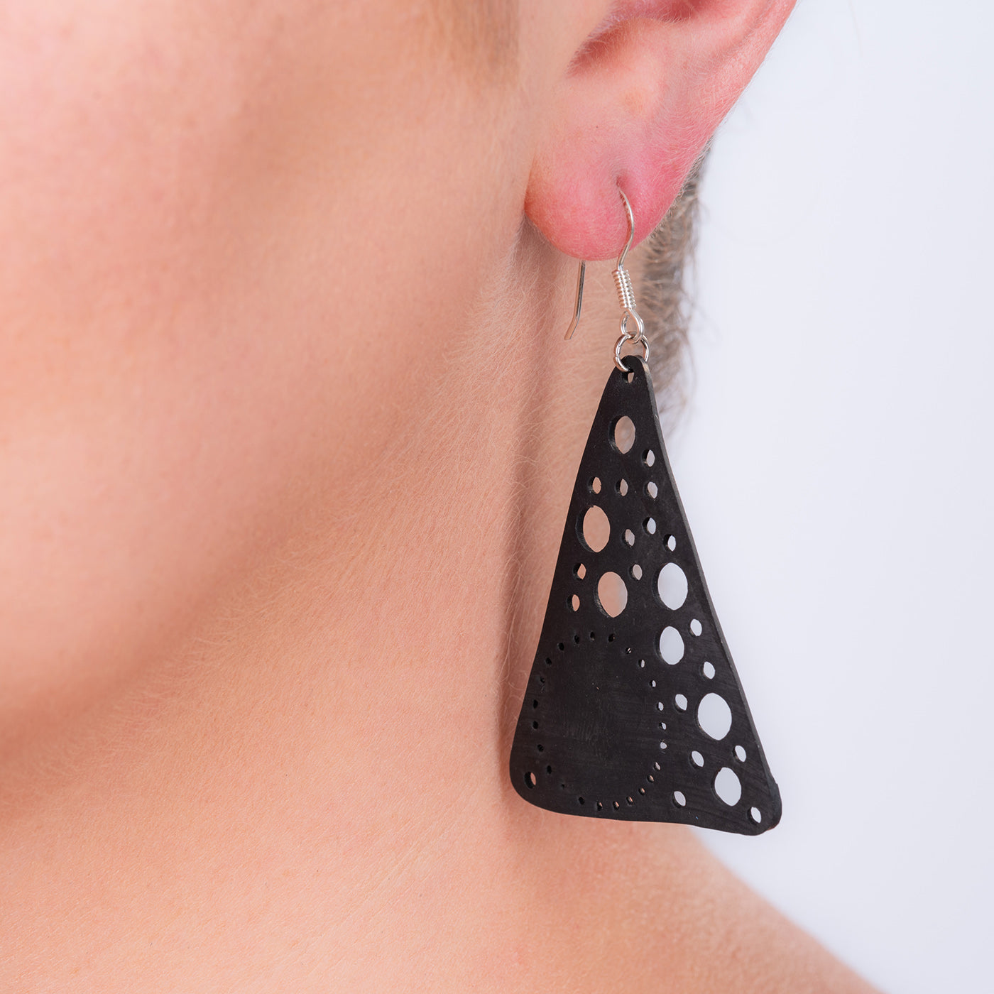 Paguro Upcycle black recycled rubber earrings with geometric cutout design worn on ear