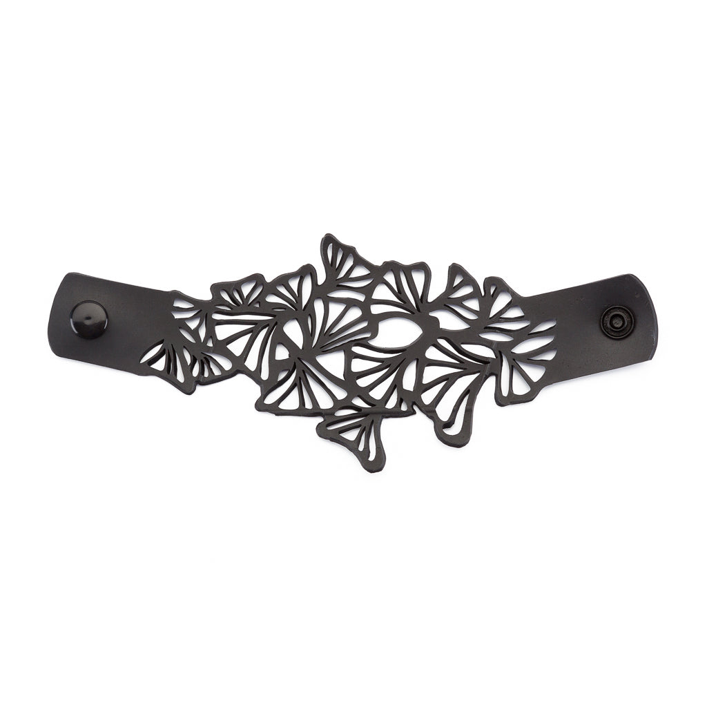 Paguro Upcycle black upcycled rubber bracelet with intricate cutout floral design and snap closure