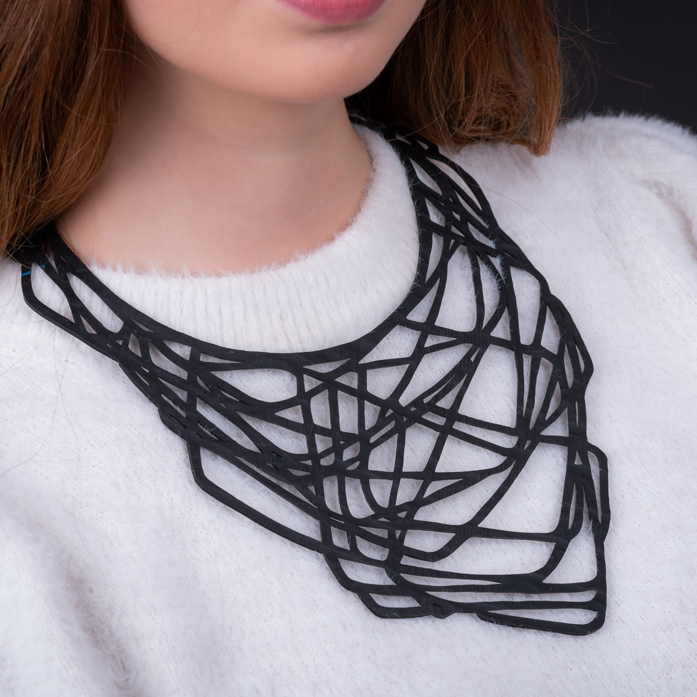 Paguro Upcycle black upcycled rubber necklace with intricate geometric design worn over white sweater