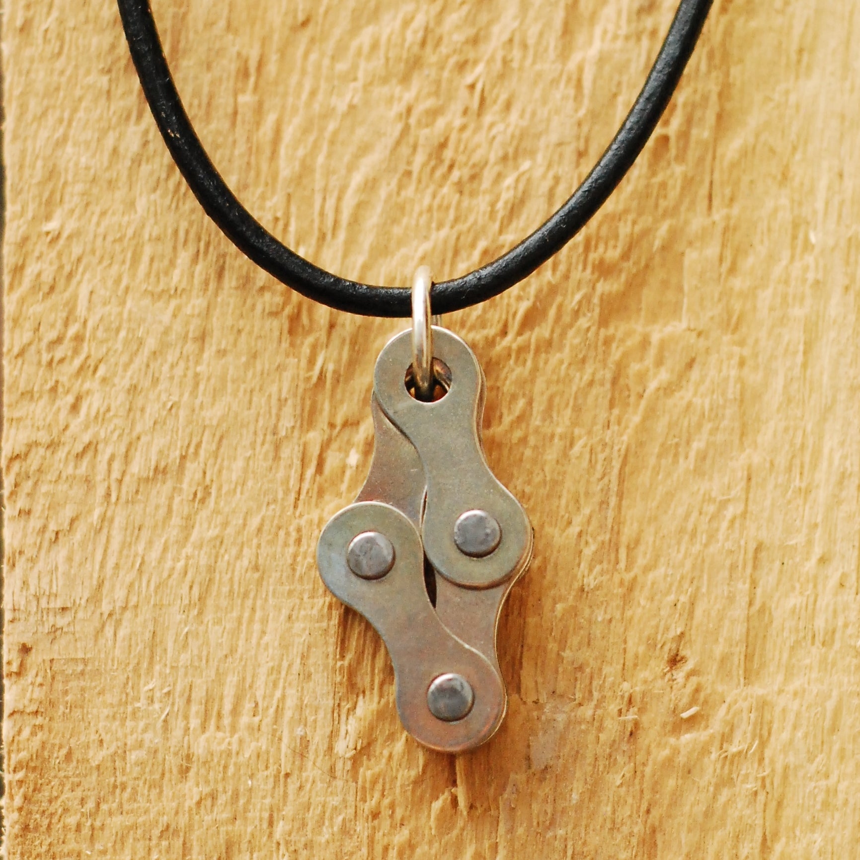 Recycled bike chain pendant necklace on a black inner tube cord, ideal for eco-conscious fashion lovers